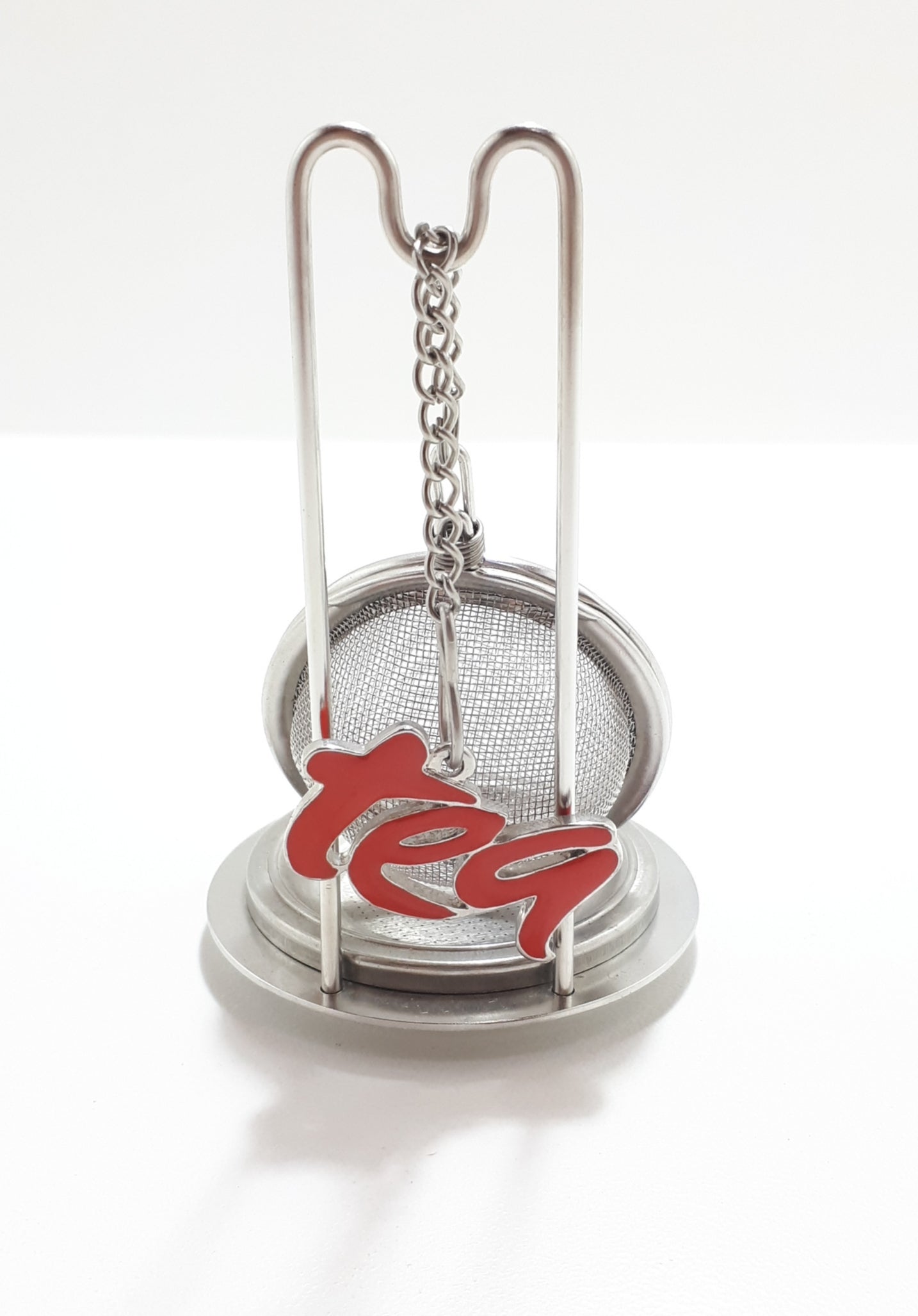 An Unused Tea Ball Strainer / Infuser With Stand, Tray & Red Enamelled “Tea” Charm